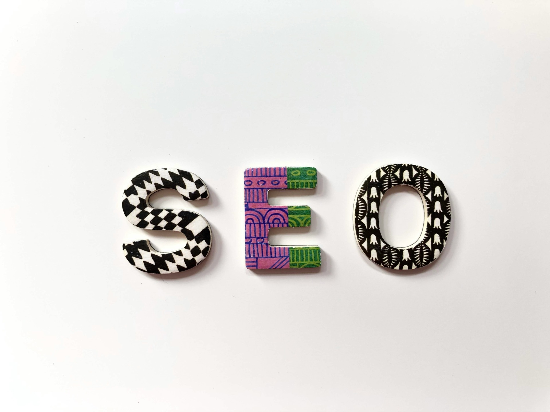Schriftzug SEO aus bunten Perlen auf weißem Hintergrund