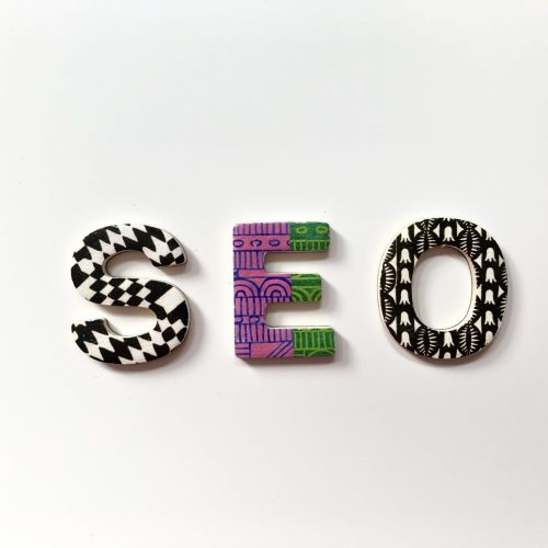 Schriftzug SEO aus bunten Perlen auf weißem Hintergrund